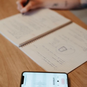 Personne assise à une table avec un téléphone et un carnet ouvert